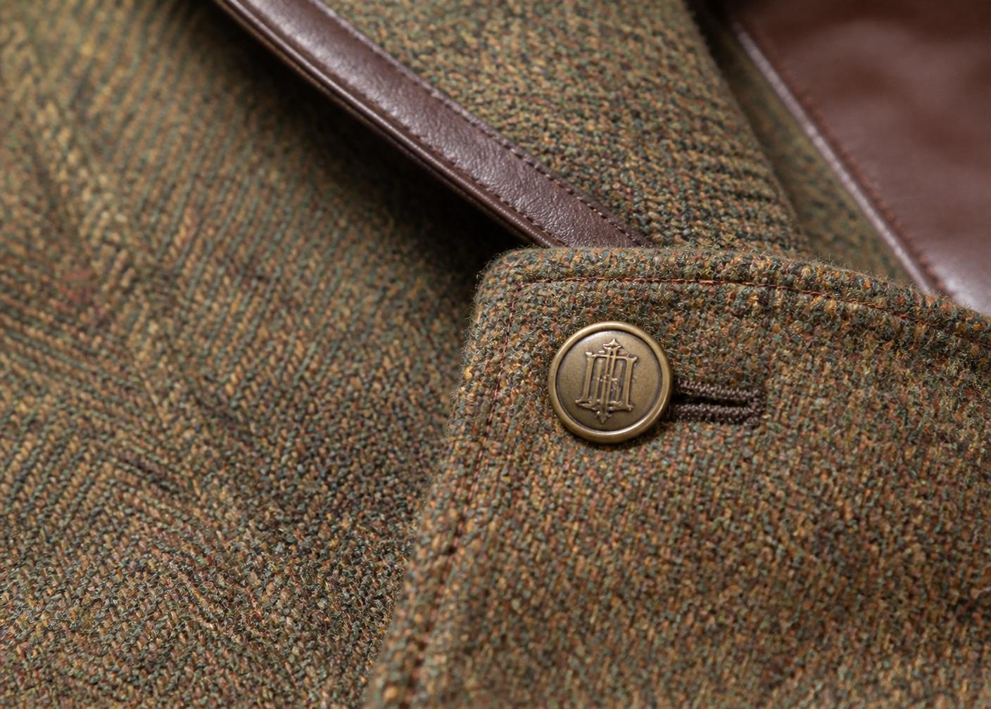 Close-up of British tweed with a hand-stitched brass button and leather trim